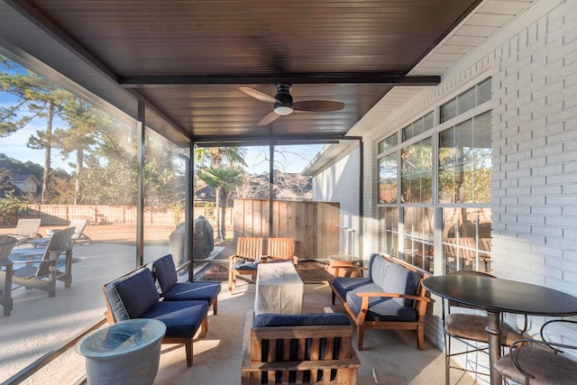 exterior space with beamed ceiling, ceiling fan, and a healthy amount of sunlight