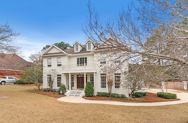 view of front facade featuring a porch, a balcony, and a front yard