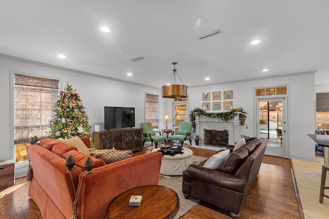 living room featuring hardwood / wood-style flooring, ornamental molding, and a fireplace