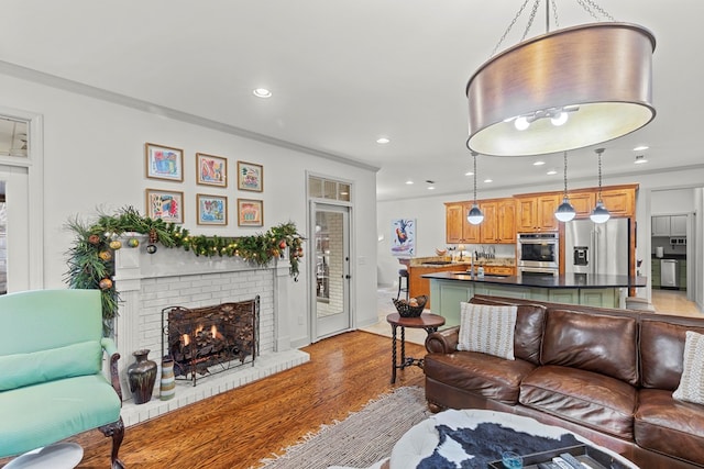 living room with ornamental molding, light hardwood / wood-style flooring, and a brick fireplace