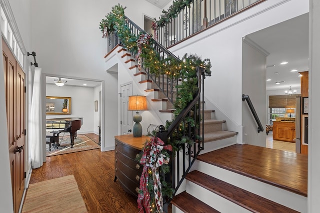 staircase featuring hardwood / wood-style floors, a towering ceiling, and a chandelier