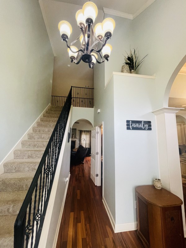 211 Paul Revere Run, Dothan, AL 36305 - staircase with arched walkways, crown molding, wood finished floors, a chandelier, and a high ceiling