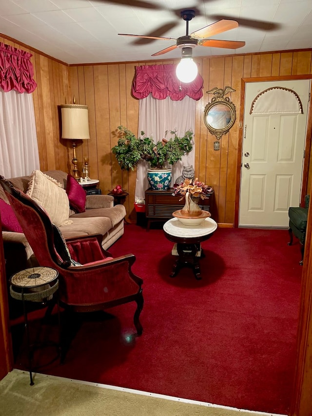 carpeted living room with wooden walls and ceiling fan