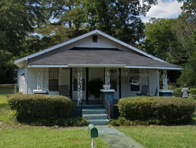 bungalow with covered porch and a front lawn