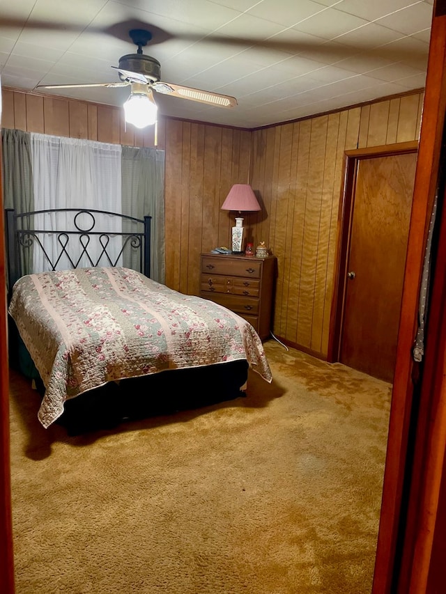 bedroom with carpet flooring, ceiling fan, and wood walls