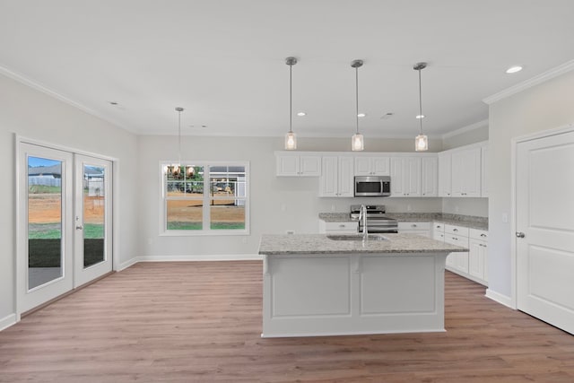 kitchen with stainless steel appliances, light stone counters, light hardwood / wood-style flooring, a center island with sink, and white cabinets