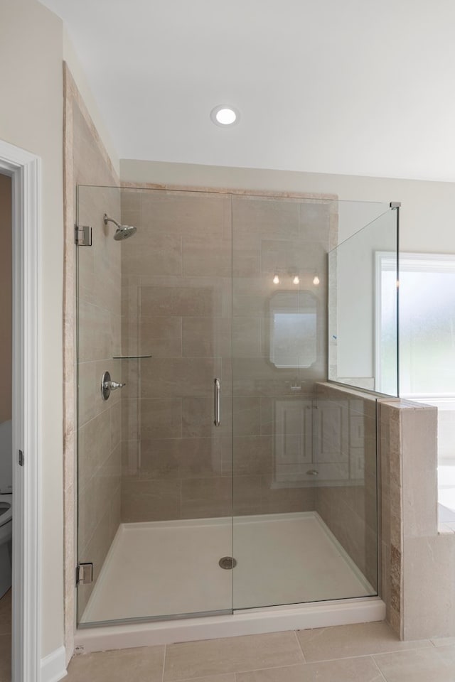 bathroom featuring toilet, tile patterned floors, and a shower with door