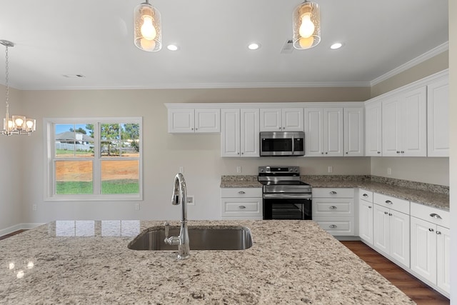 kitchen with light stone countertops, appliances with stainless steel finishes, hanging light fixtures, and sink