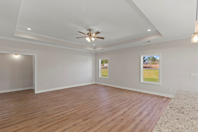 unfurnished living room featuring ceiling fan, light hardwood / wood-style floors, crown molding, and a tray ceiling