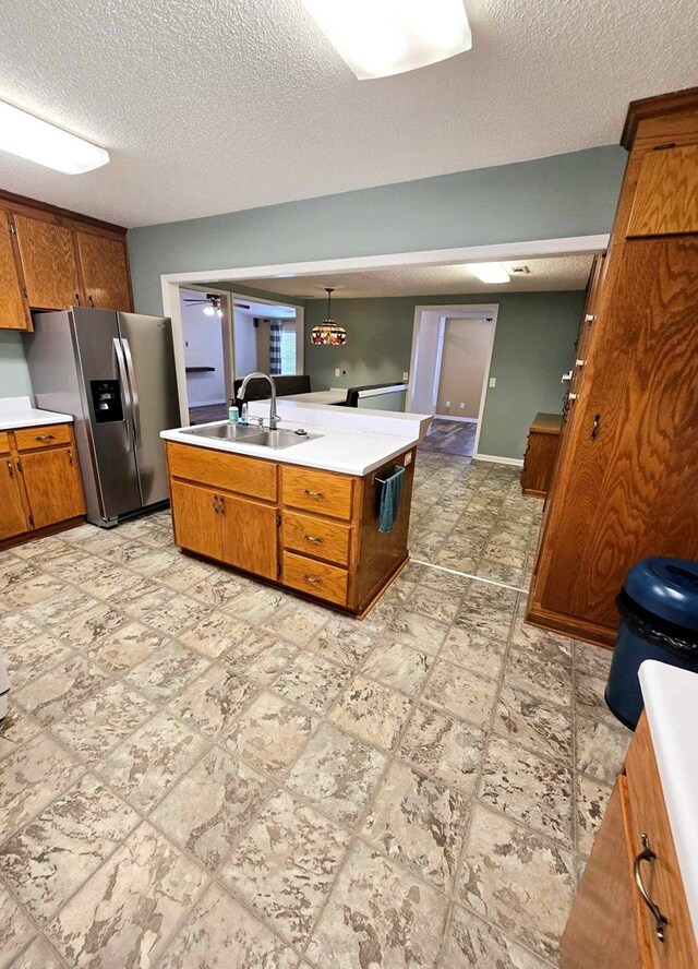 653 Honeysuckle Hills Rd, Ozark, AL 36360 - kitchen featuring stainless steel fridge, a sink, a textured ceiling, brown cabinets, and light countertops