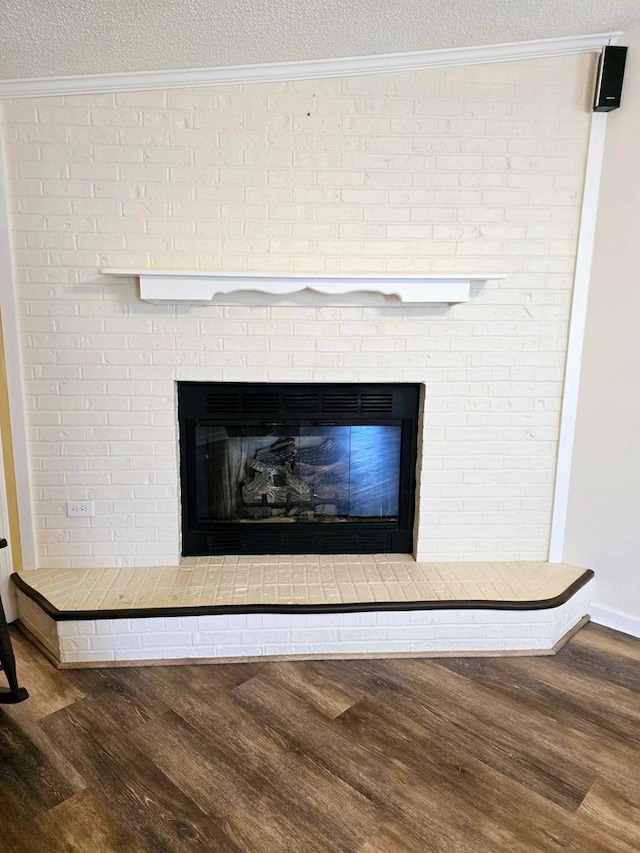 653 Honeysuckle Hills Rd, Ozark, AL 36360 - detailed view of a brick fireplace, wood finished floors, ornamental molding, and a textured ceiling