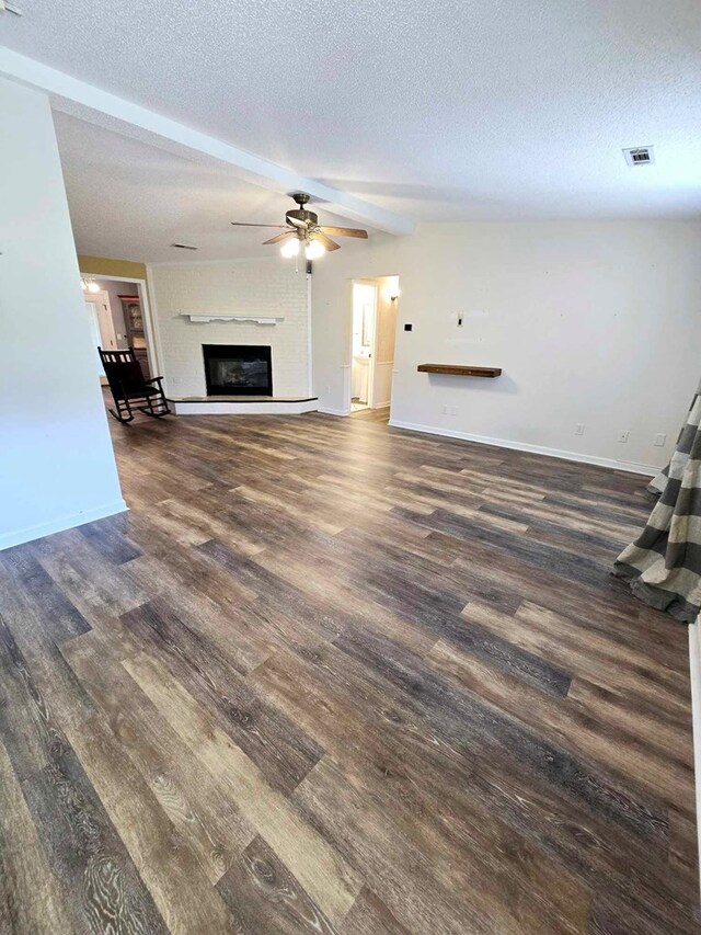 653 Honeysuckle Hills Rd, Ozark, AL 36360 - unfurnished living room with a textured ceiling, wood finished floors, a glass covered fireplace, baseboards, and beam ceiling