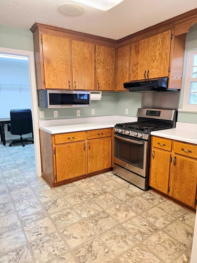 653 Honeysuckle Hills Rd, Ozark, AL 36360 - kitchen with appliances with stainless steel finishes, under cabinet range hood, light countertops, brown cabinetry, and a textured ceiling
