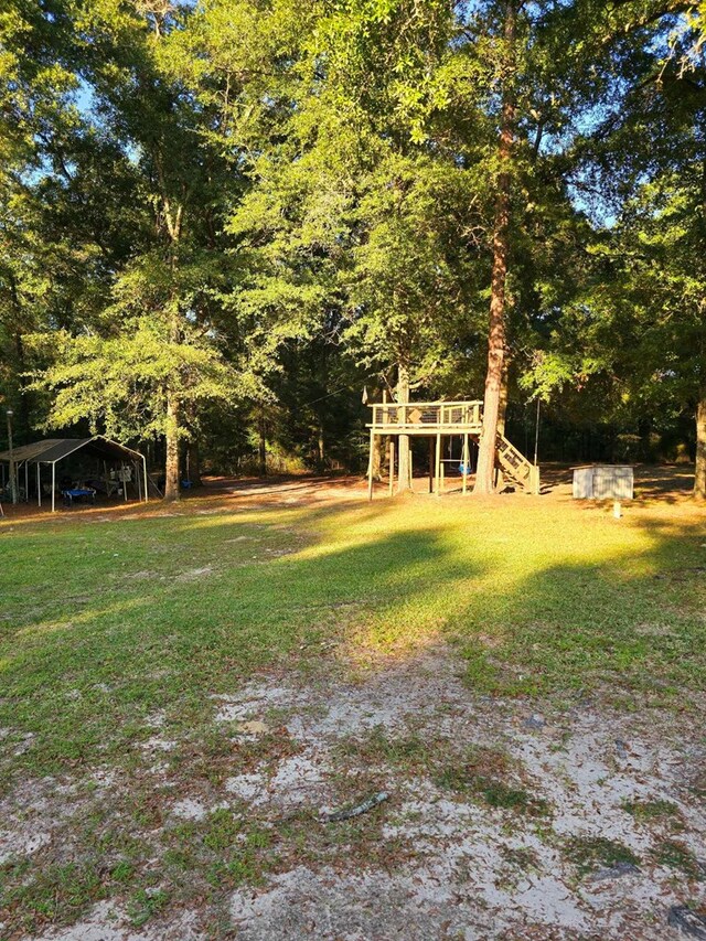 653 Honeysuckle Hills Rd, Ozark, AL 36360 - view of green lawn featuring stairway, a carport, and a deck