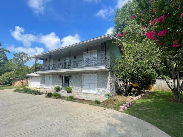 view of front of house featuring a front lawn, a garage, and a balcony