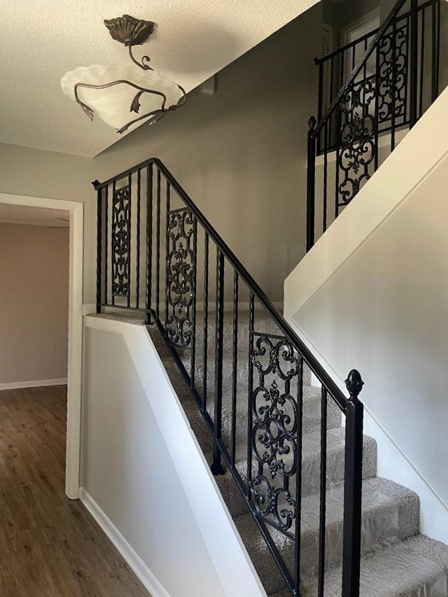 stairs featuring a textured ceiling and wood-type flooring