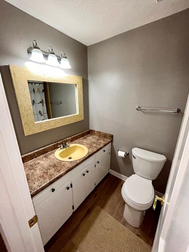 bathroom featuring hardwood / wood-style flooring, toilet, vanity, and a textured ceiling