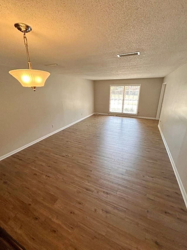 empty room featuring dark wood-type flooring and a textured ceiling