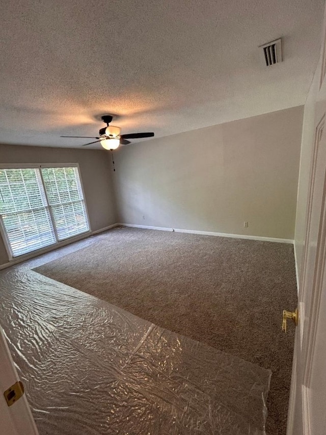 empty room featuring ceiling fan, carpet flooring, and a textured ceiling