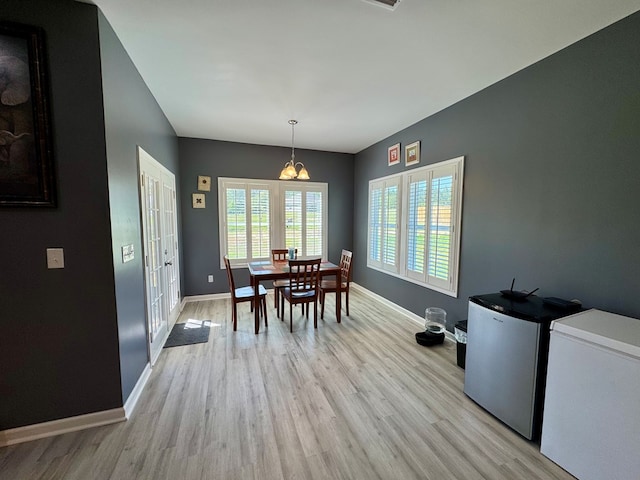 dining space featuring light wood-type flooring, baseboards, and a chandelier