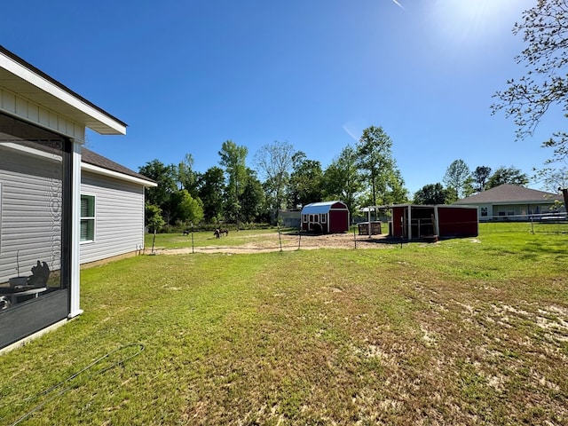 view of yard with fence, an outbuilding, and a shed