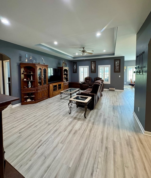 living area featuring arched walkways, recessed lighting, a ceiling fan, wood finished floors, and a raised ceiling