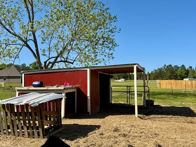 view of outdoor structure with fence and an outbuilding