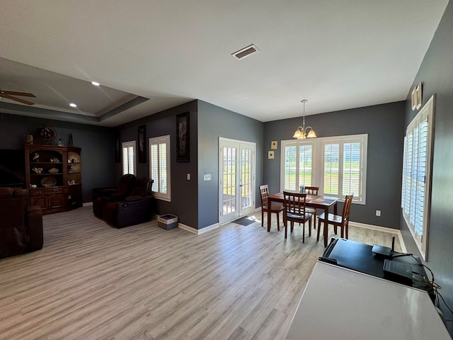 dining space with a healthy amount of sunlight, light wood-style floors, visible vents, and ceiling fan with notable chandelier