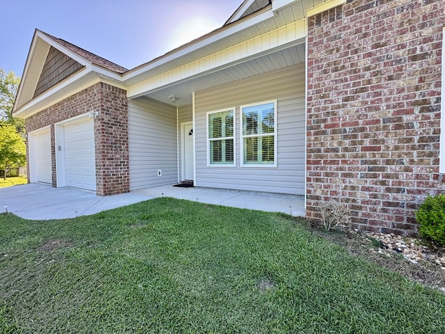 exterior space with brick siding, a yard, an attached garage, and driveway