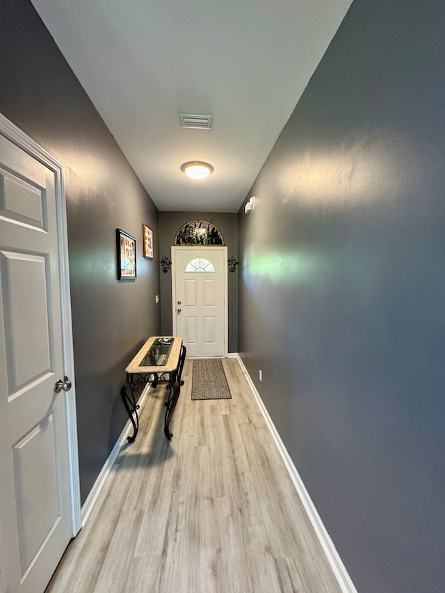 doorway with baseboards, wood finished floors, and visible vents
