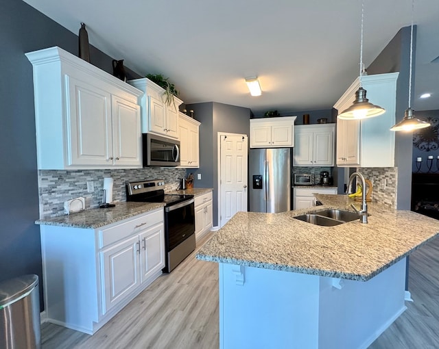 kitchen featuring a breakfast bar, a sink, light wood-style floors, a peninsula, and appliances with stainless steel finishes