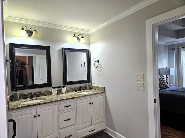 full bath featuring crown molding, double vanity, baseboards, and a sink