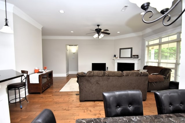 living room featuring a ceiling fan, recessed lighting, ornamental molding, and wood finished floors