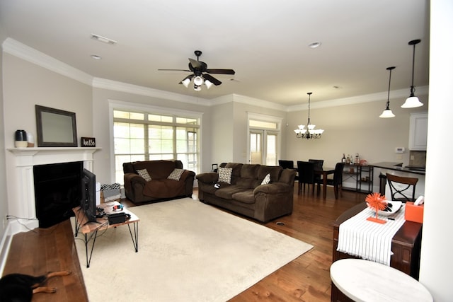 living area featuring visible vents, ornamental molding, wood finished floors, and ceiling fan with notable chandelier