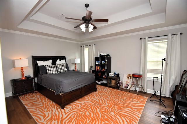 bedroom featuring a raised ceiling, a ceiling fan, baseboards, wood finished floors, and visible vents