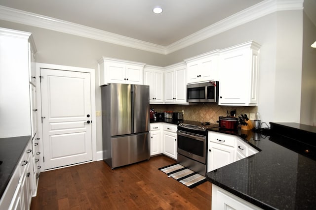 kitchen with appliances with stainless steel finishes, tasteful backsplash, dark wood-style flooring, and white cabinetry