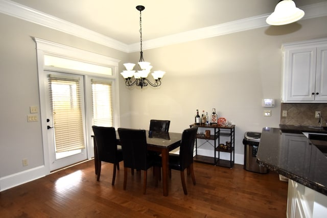 dining area with dark wood-style flooring, baseboards, a notable chandelier, and ornamental molding