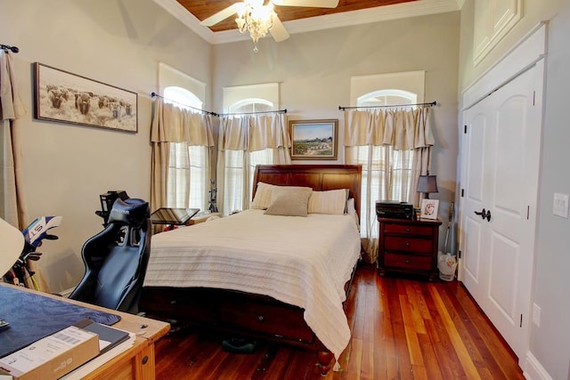 bedroom featuring ceiling fan, crown molding, dark wood-type flooring, and a closet