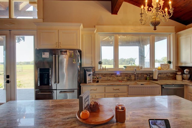 kitchen with light stone countertops, sink, stainless steel appliances, vaulted ceiling with beams, and a notable chandelier