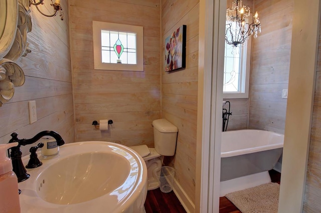 bathroom featuring toilet, wood walls, a bathtub, and sink