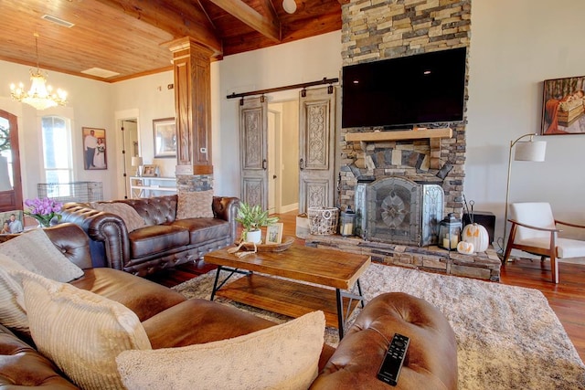 living room with wood ceiling, beam ceiling, hardwood / wood-style flooring, an inviting chandelier, and a stone fireplace