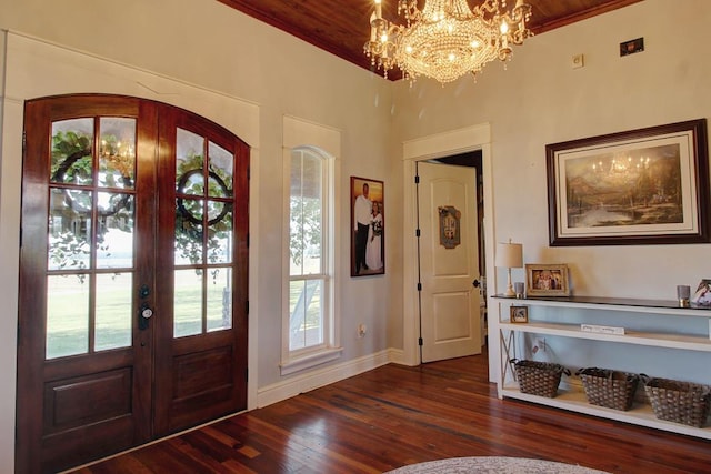 foyer entrance with french doors, wooden ceiling, dark hardwood / wood-style floors, a notable chandelier, and ornamental molding