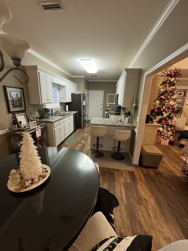 kitchen featuring stainless steel fridge, stove, dark wood-type flooring, crown molding, and white cabinetry