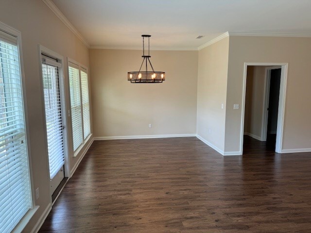 spare room featuring ornamental molding, dark hardwood / wood-style floors, and a notable chandelier