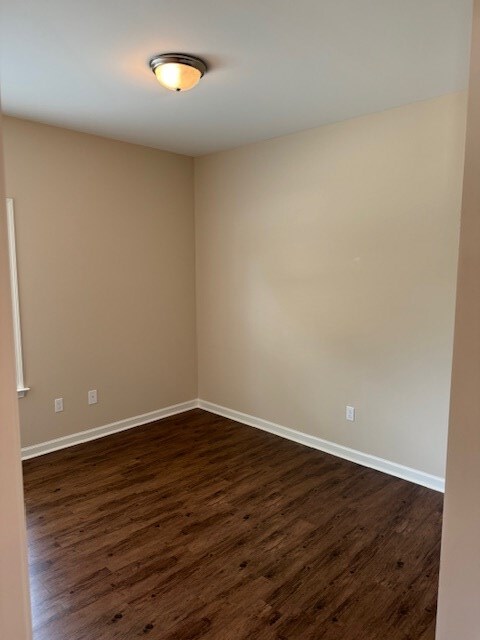 unfurnished room featuring dark wood-type flooring