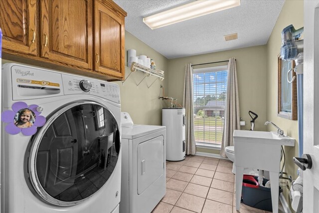 24 County Road 278, Enterprise, AL 36330 - laundry area with water heater, washing machine and clothes dryer, a textured ceiling, and light tile patterned flooring