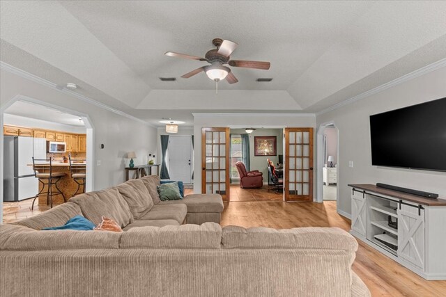 24 County Road 278, Enterprise, AL 36330 - living room featuring arched walkways, a raised ceiling, a ceiling fan, crown molding, and light wood-style flooring