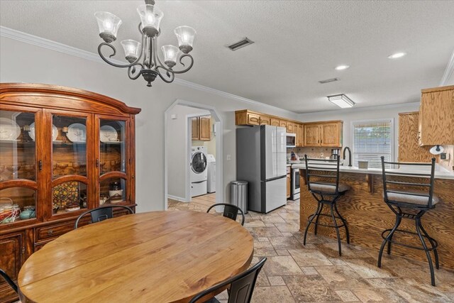 24 County Road 278, Enterprise, AL 36330 - dining area featuring washer / dryer, ornamental molding, arched walkways, stone tile floors, and a chandelier