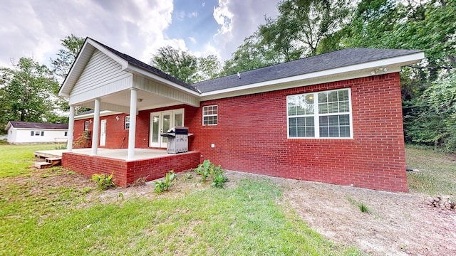 rear view of house featuring a lawn, a patio area, and brick siding