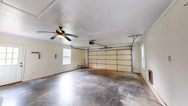 garage featuring a garage door opener, a ceiling fan, and baseboards